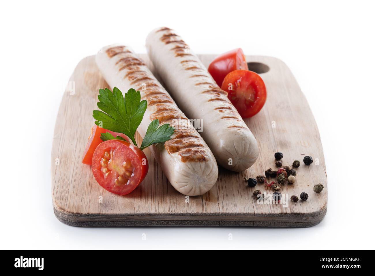 Salsicce Bratwurst grigliate con pomodori ciliegini e prezzemolo isolati su sfondo bianco Foto Stock