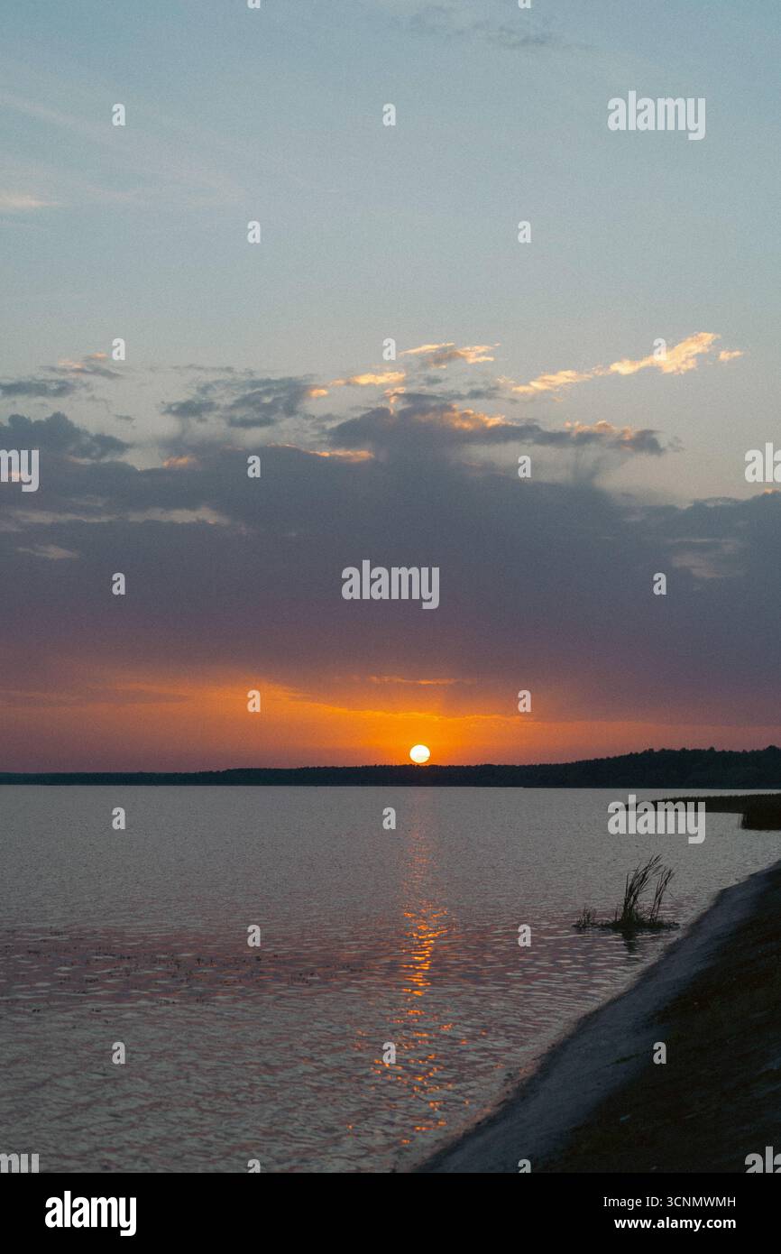 Tramonto mozzafiato su un lago calmo con riflessi e cielo colorato Foto Stock