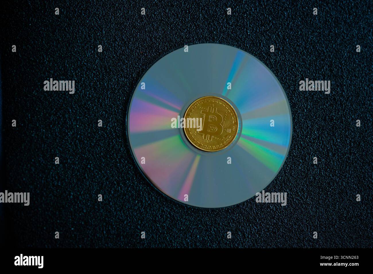 Moneta Golden Bitcoin collocata su un compact disc che simboleggia la valuta digitale, l'archiviazione dei dati e la moderna tecnologia finanziaria Foto Stock