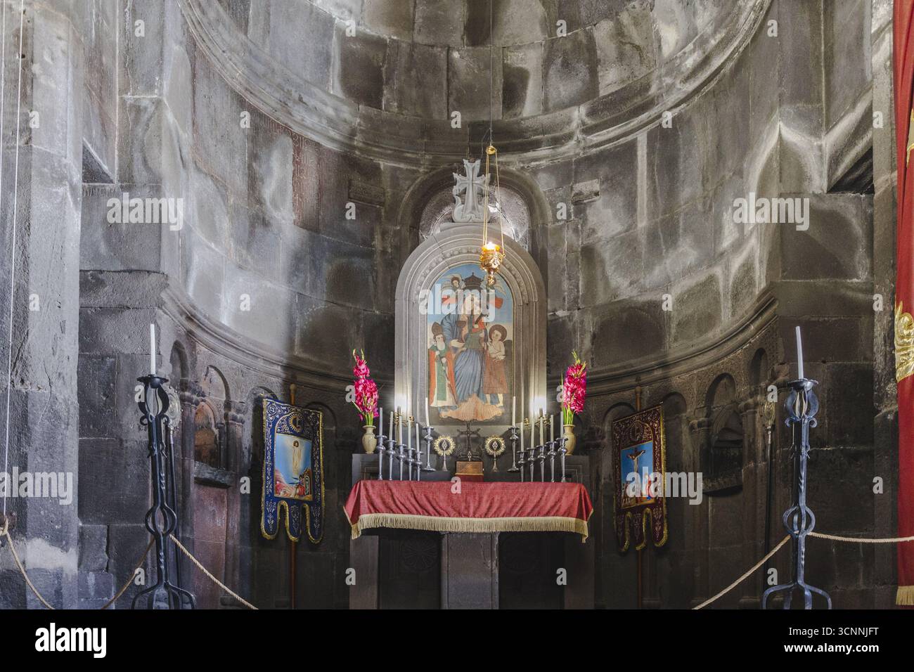 Vista di un sereno altare adornato da fiori vivaci e iconografia religiosa, che getta un bagliore tra le antiche mura di pietra, Mets Gilanlar, Ararat Pr Foto Stock