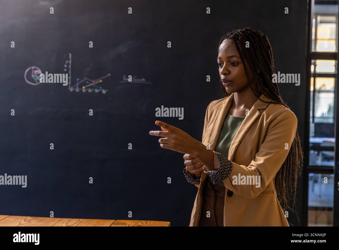 Donna afroamericana che presenta diagrammi di gesso su lavagna, copia spazio Foto Stock