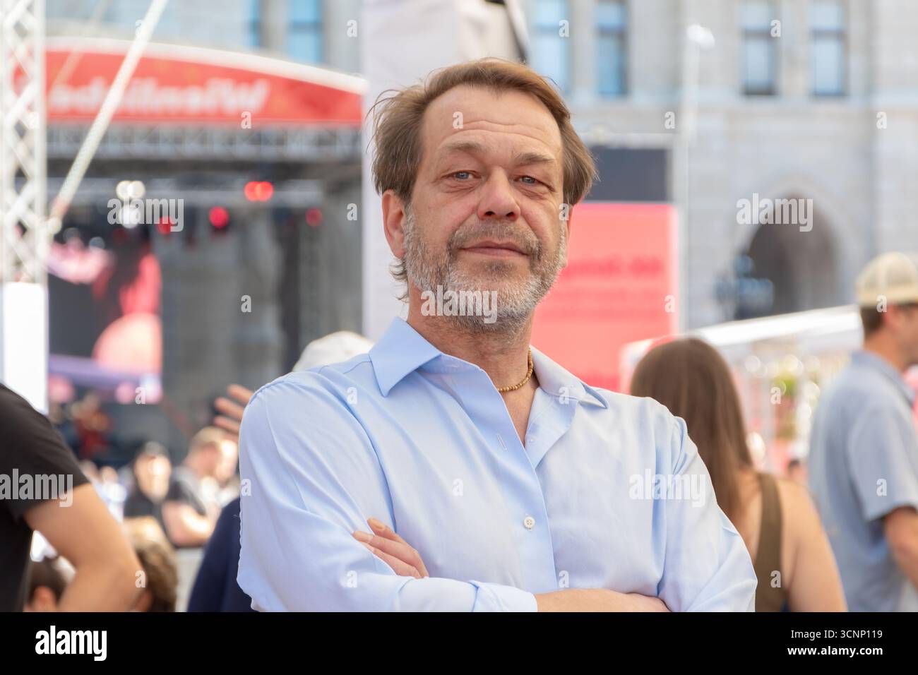 Un uomo anziano con la barba posa per strada tra le persone Foto Stock
