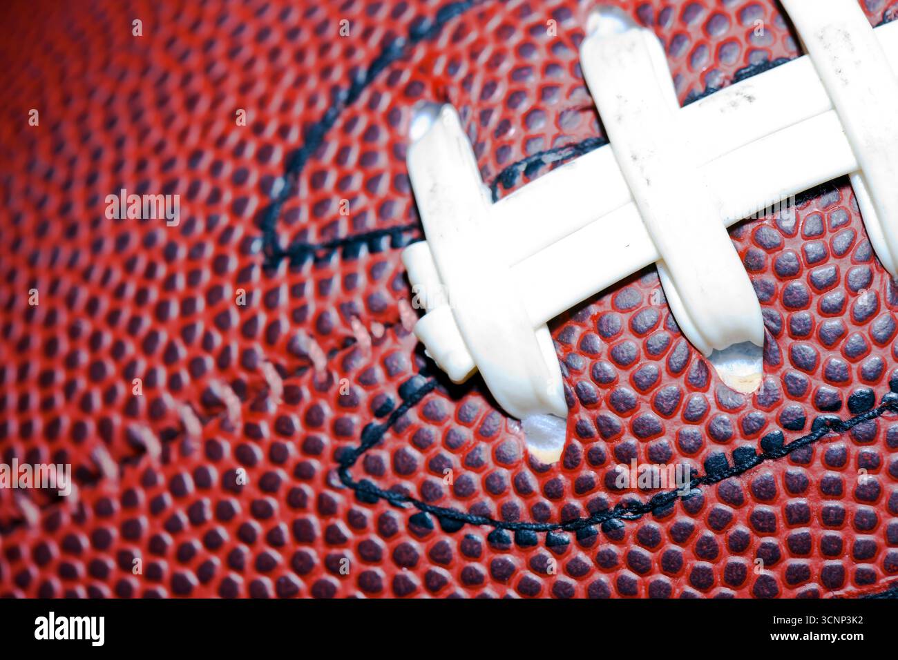 Un primo piano di un football americano rivela una texture dettagliata della pelle e cuciture precise, fotografate in uno studio su sfondo nero, Highli Foto Stock