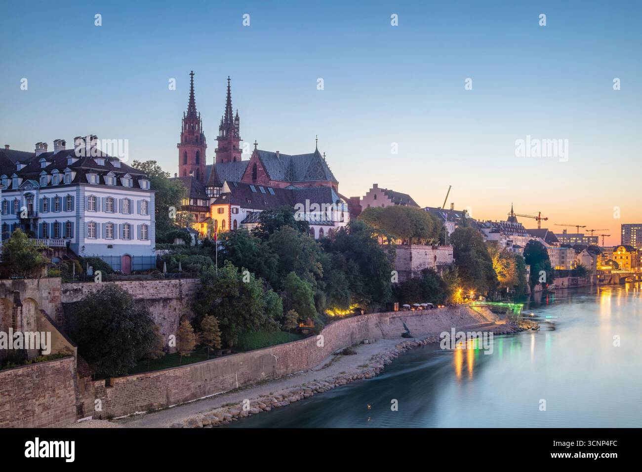 Basilea, Svizzera - Vista della riva sinistra del Reno con la città vecchia e la cattedrale di Baseler Munster al crepuscolo Foto Stock