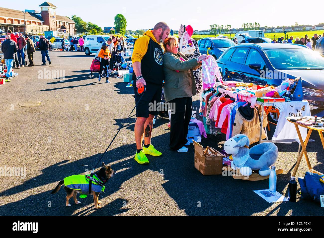 Uomo e donna che guardano i vestiti di seconda mano da una stalla in un mercato di strada, Ayr, Ayrshire, Scozia, Regno Unito Foto Stock