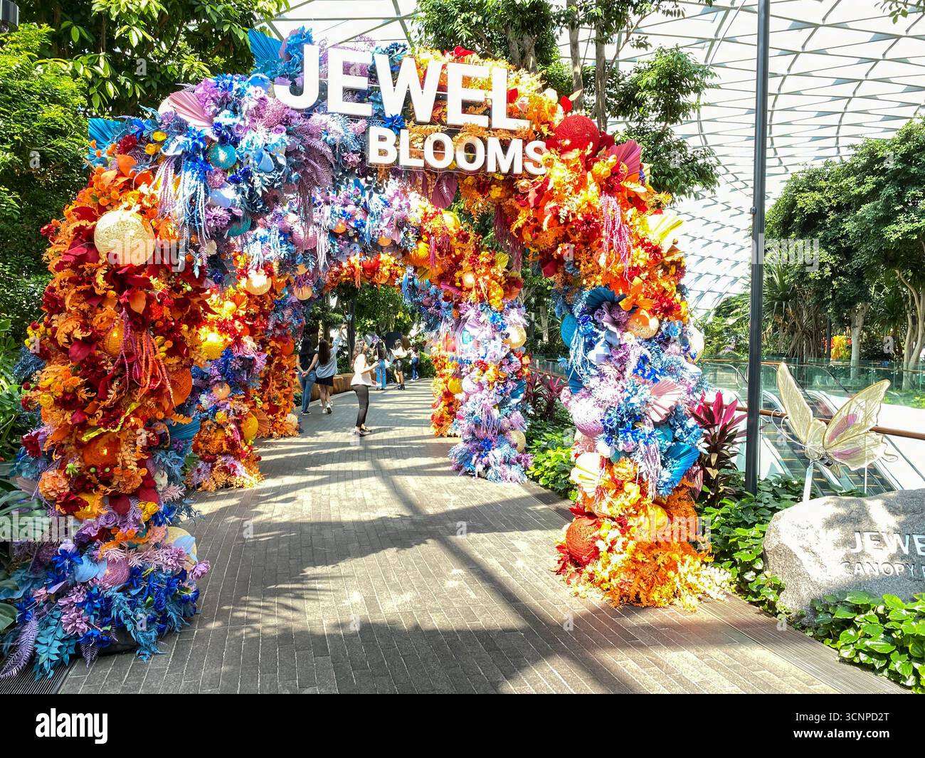 Ingresso principale per i visitatori presso i Jewel Blooms, decorato con plastica colorata e fiori di carta nello stesso aerostazione dell'indù più alto del mondo - Immagine stock catturata con smartphone
