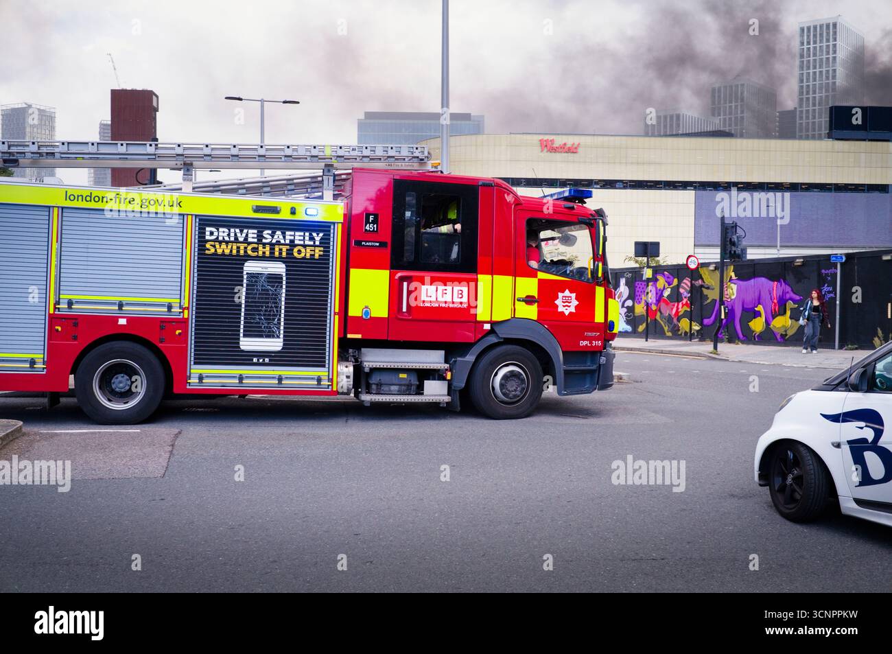 Un pompiere di Londra si dirige verso il centro Westfield a Stratford, dove i veicoli sono in fiamme nel parcheggio Foto Stock