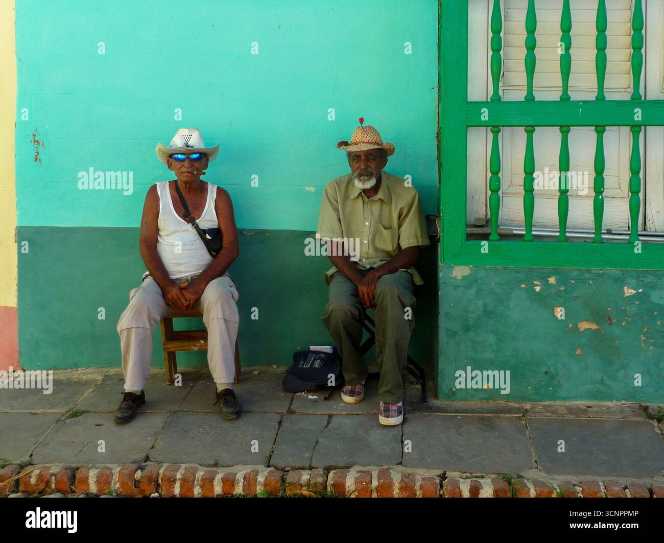 Cuba - Trinidad - Plaza Mayor - due anziani seduti da una facciata verde nel centro storico Foto Stock