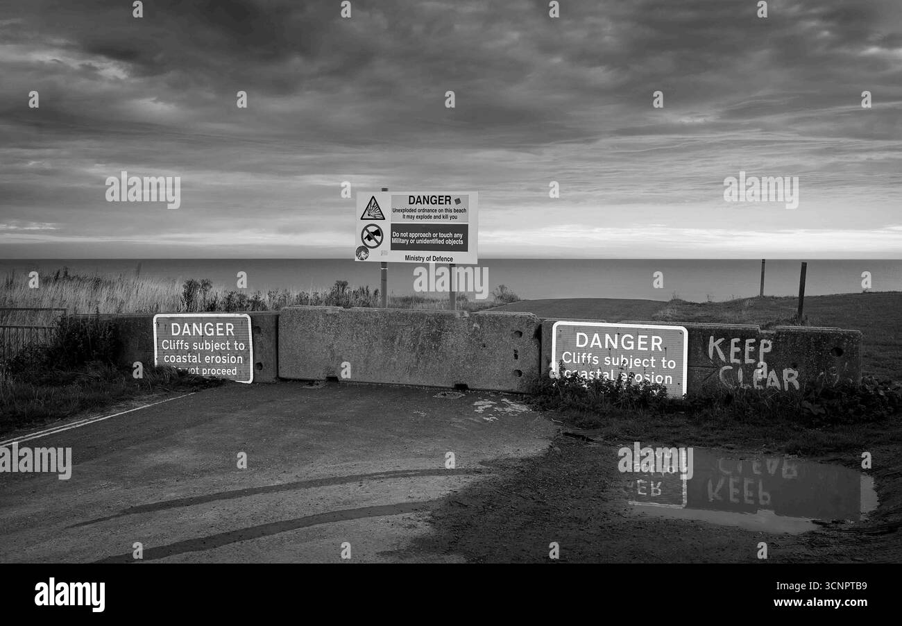 Segnali di grave erosione costiera e stradale, con segnali di pericolo di ordigni inesplosi risalenti alla guerra mondiale. Aldbrough. Foto Stock