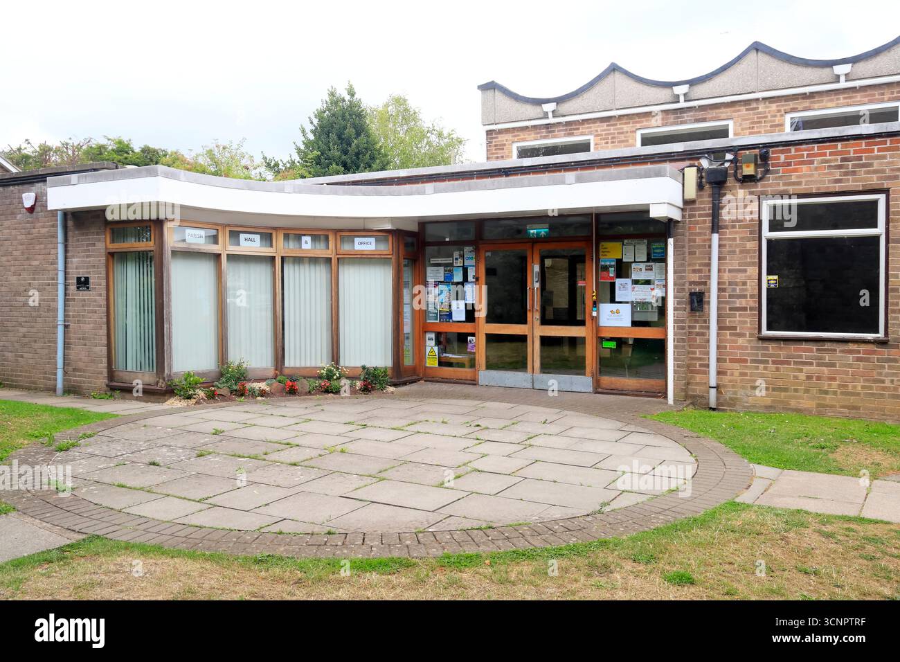 Moderno Brick Community Centre dietro la chiesa di San Giovanni Battista, il centro città di Keynsham, Somerset, Inghilterra occidentale. Data: Luglio 2025. Estate Foto Stock