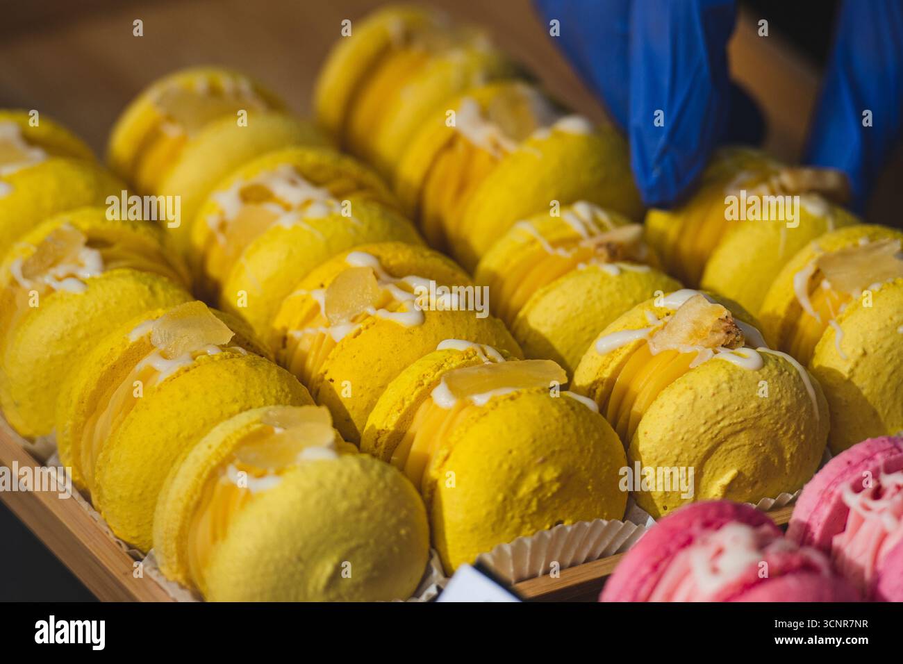 Primo piano di macaron gialli disposti in righe visualizzate. Colorato dessert francese con ripieno di panna, decorato con glassa e guarnizioni Foto Stock