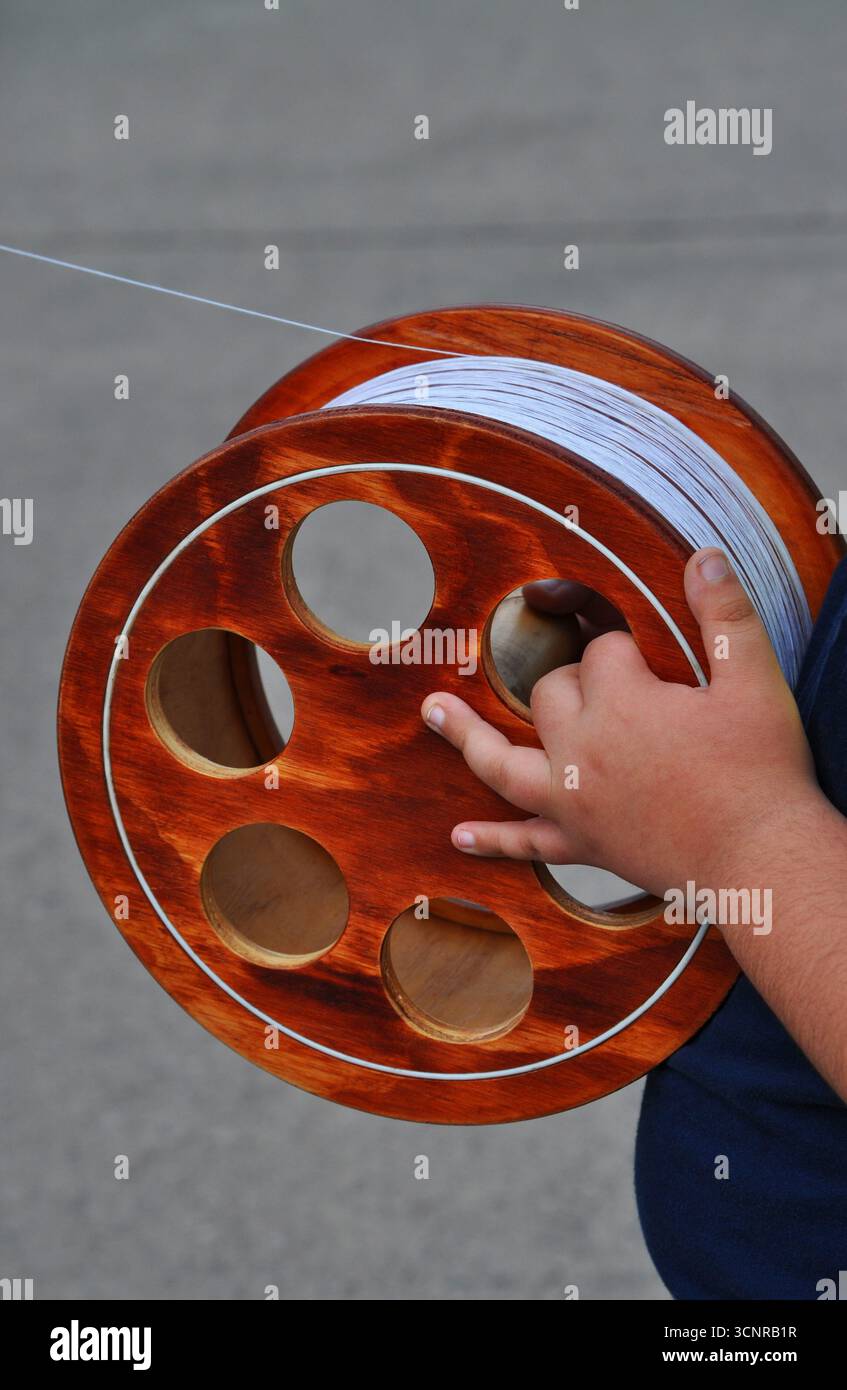 Le mani del bambino reggono una bobina di filo per far volare un aquilone Foto Stock