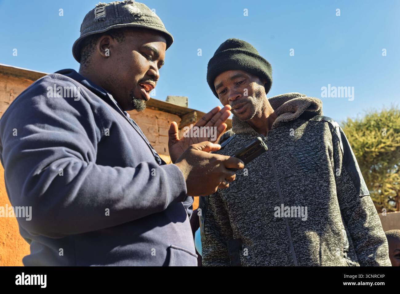 villaggio africano, educazione degli assistenti sociali di beneficenza che spiega a un imprenditore paesano i vantaggi delle comunicazioni mobili e del software per sfuggire al po Foto Stock