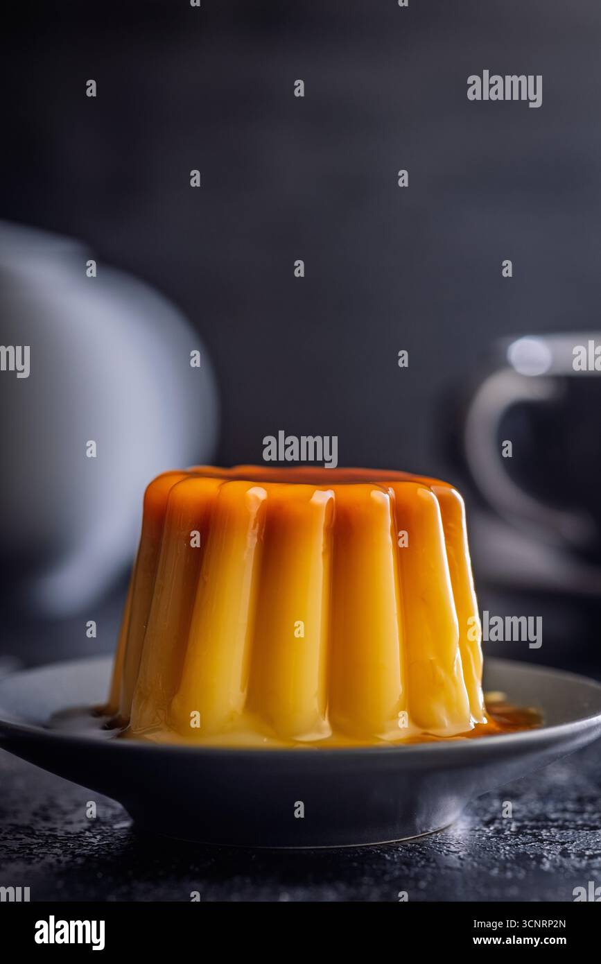 Budino alla vaniglia con salsa al caramello su un tavolo nero. Foto Stock
