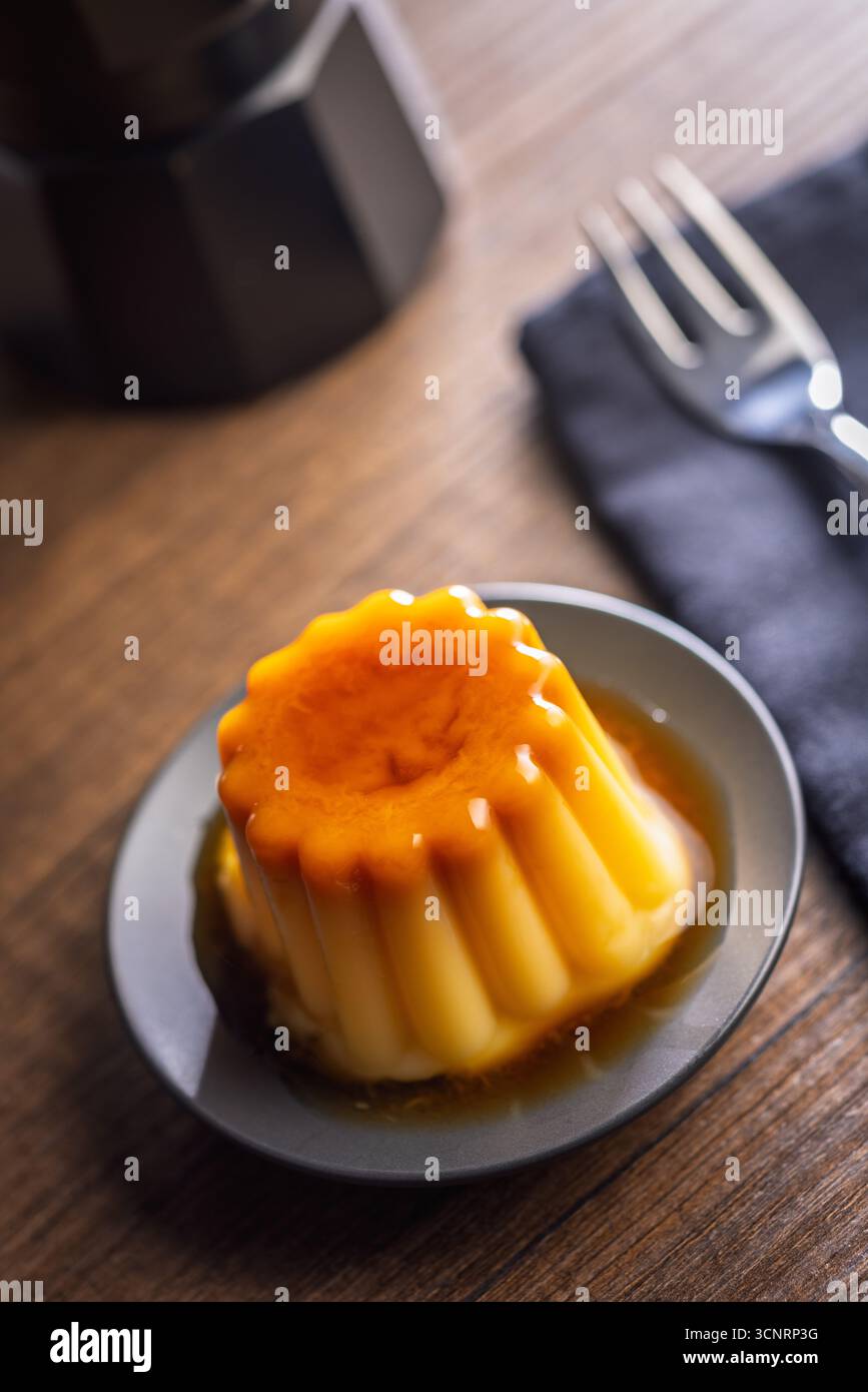 Budino alla vaniglia con salsa al caramello su un tavolo di legno. Foto Stock