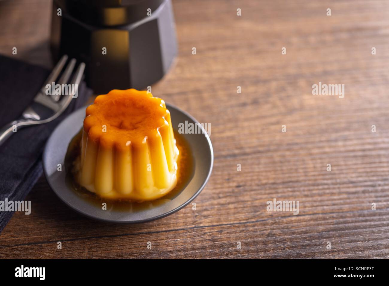 Budino alla vaniglia con salsa al caramello su un tavolo di legno. Foto Stock