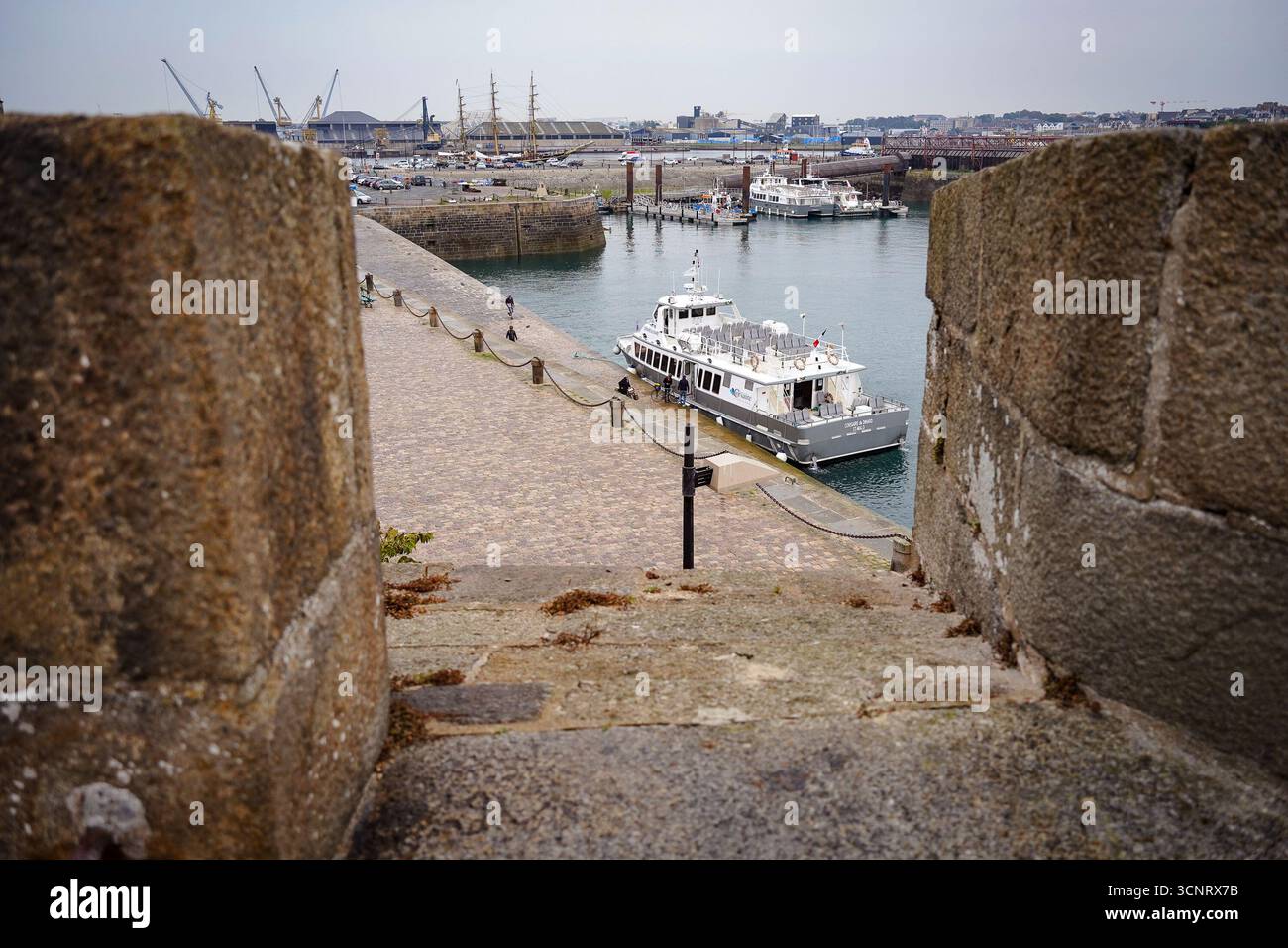 Barca a vela vicino ai bastioni storici di Saint-Malo, la costa della Bretagna. Le mura medievali incontrano il mare in una vivace scena marittima. Foto Stock