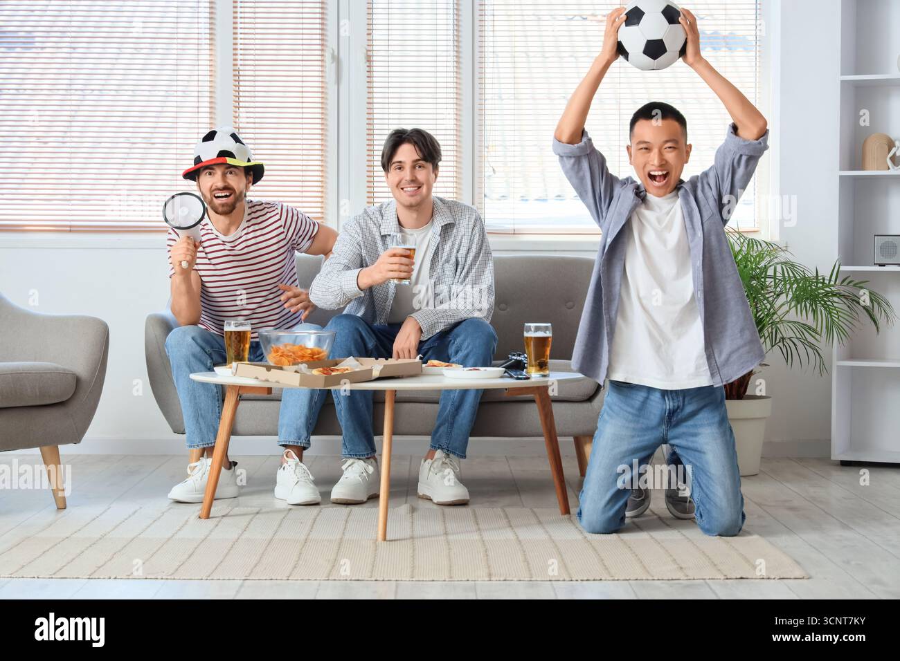 Amici maschi con birra che guardano il calcio a casa Foto Stock