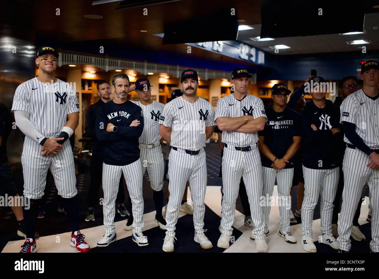 Il presidente Donald Trump parla con la squadra dei New York Yankees nel loro spogliatoio della clubhouse indossando per la NYPD e la FDNY cappelli tributo per il 9/11 prima di una partita contro i Detroit Tigers allo Yankee Stadium. I giocatori ascoltano in uniforme da pinstripe. New York, Stati Uniti. 11 settembre 2025. Foto Stock