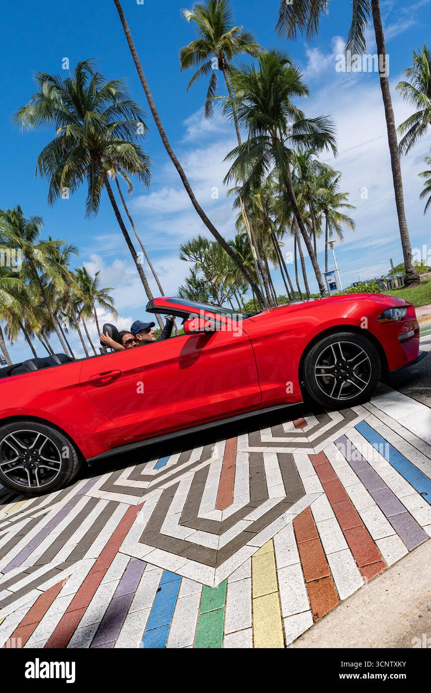 Miami Beach, Stati Uniti. 22 settembre 2025. Un'auto passa oltre i vialetti dell'orgoglio che sono ancora visibili all'incrocio tra Ocean Dr. E 12th Street. Il Dipartimento dei trasporti della Florida sotto la direzione del governatore Ron DeSantis ha ordinato la rimozione di tutte le balestre arcobaleno nello stato. Miami Beach sta combattendo la regola in tribunale e i loro sono uno degli unici incroci rimasti su cui non hanno dipinto. Credito: SOPA Images Limited/Alamy Live News Foto Stock