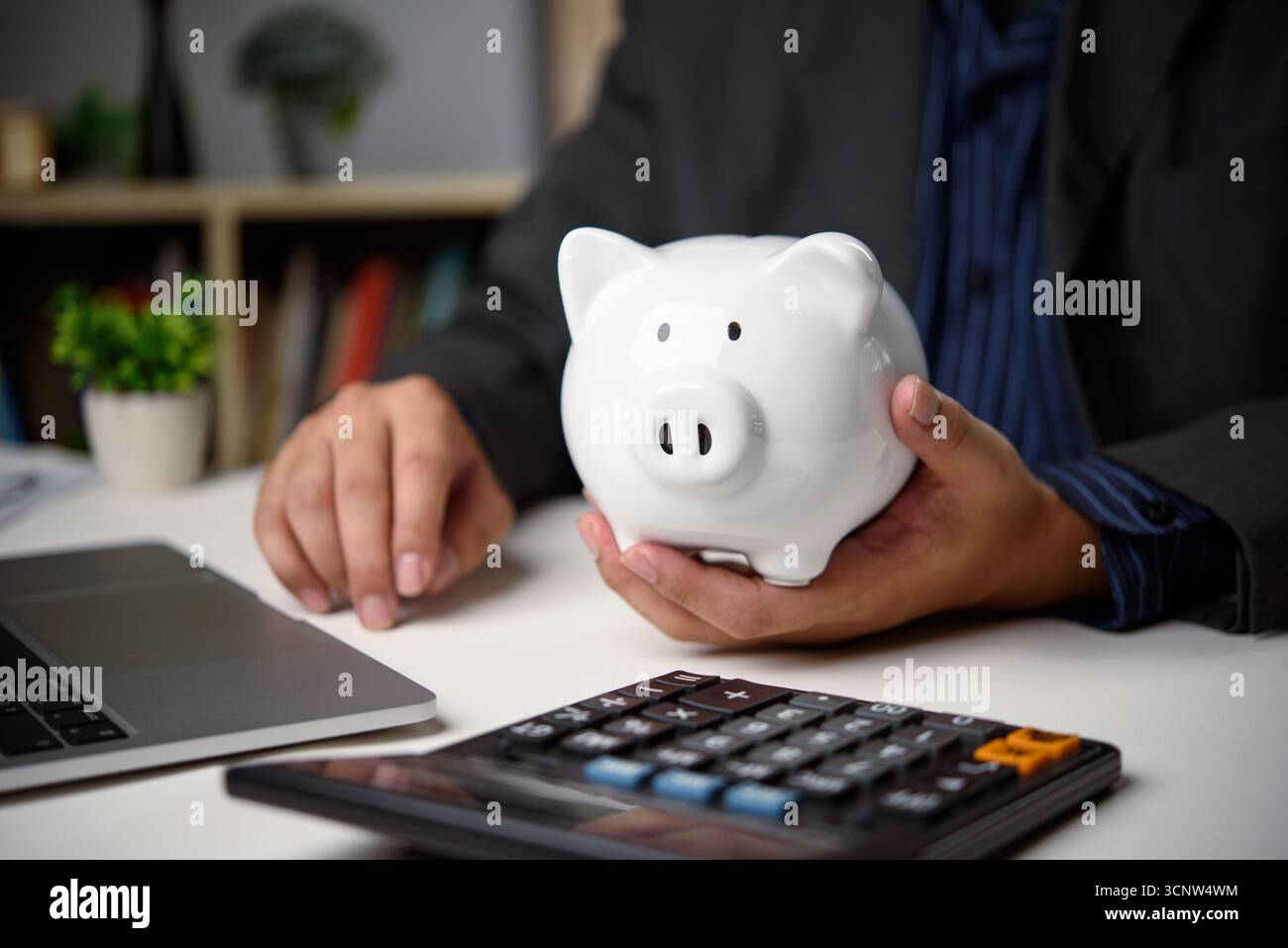 Uomo d'affari che risparmia denaro con il salvadanaio e la calcolatrice. Pianificazione finanziaria, gestione del bilancio e strategia di ricchezza personale per la crescita economica e fin Foto Stock