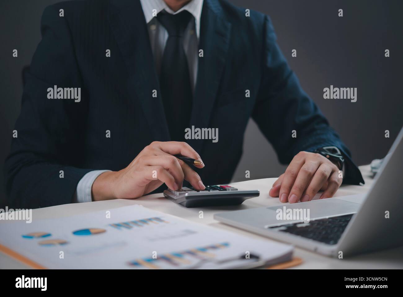 Professionista finanziario che utilizza calcolatrice e penna, contabilità per la gestione del budget, analisi dei dati aziendali e pianificazione finanziaria meticolosa per gli investitori Foto Stock