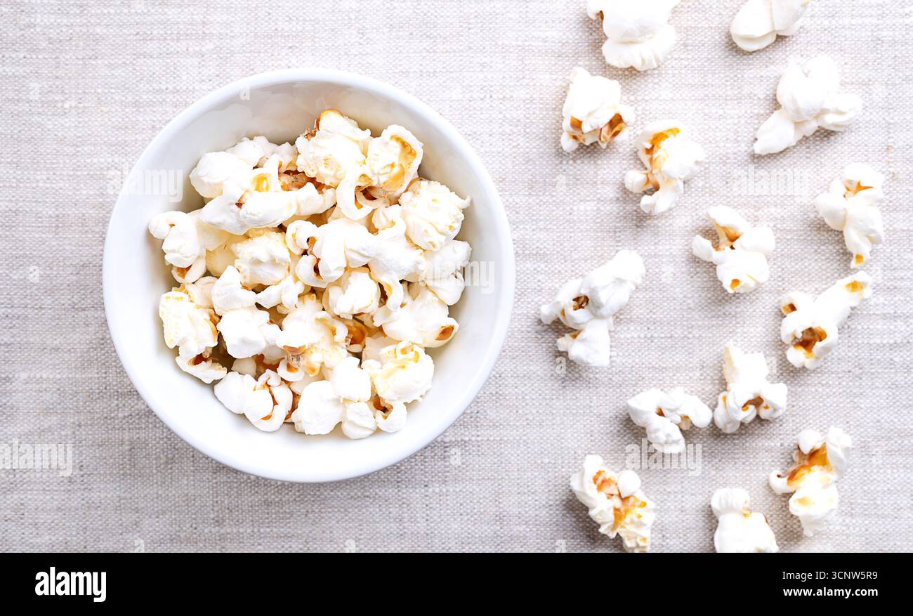 Pop corn, mais in un recipiente bianco su lino. Semi della varietà Zea mays everta, espansi e gonfiati, dopo essere stati riscaldati. Snack. Foto Stock