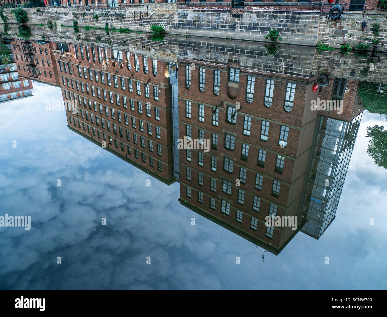 Riflesso del vecchio magazzino convertito in appartamenti in acqua del canale Foto Stock