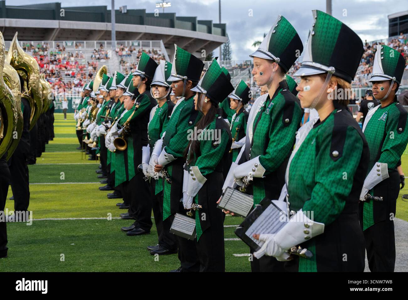Vestite con uniformi vivaci, i membri della banda della University of Hawaii si stanno formando, pronti ad accendere lo stadio con il suono e lo spirito scolastico Foto Stock