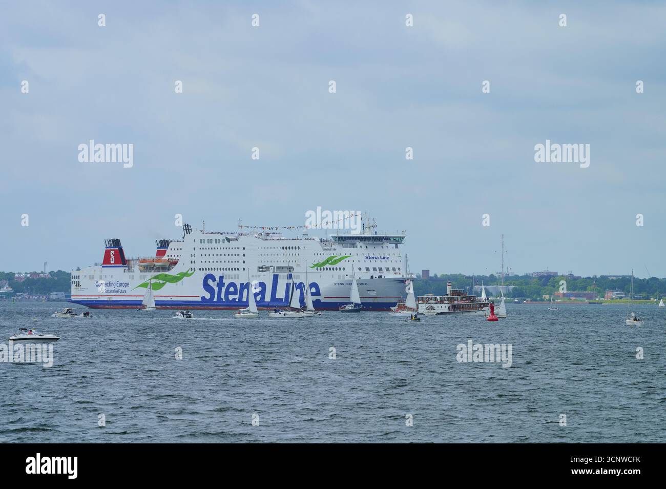 Grande traghetto della Stena Line sul mare, circondato da piccole barche a vela sotto un cielo nuvoloso, Windjammer Parade Kiel 2025, Heikendorf, Kreis Ploen, Kiele Foto Stock
