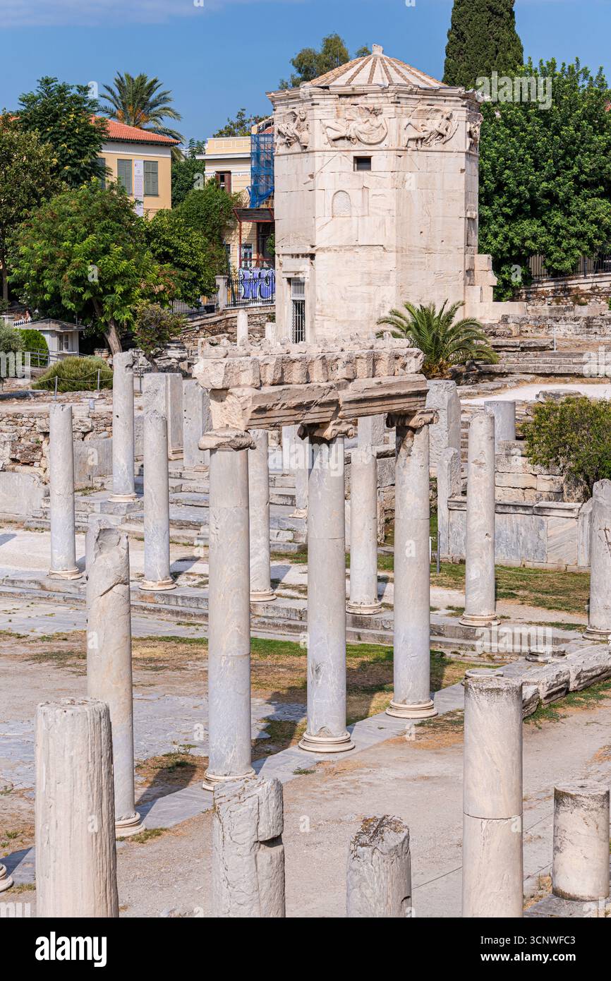 Una vista pittoresca delle antiche rovine di Atene caratterizzata da colonne classiche e architettura storica circondata da lussureggiante vegetazione sotto un cielo azzurro. Foto Stock