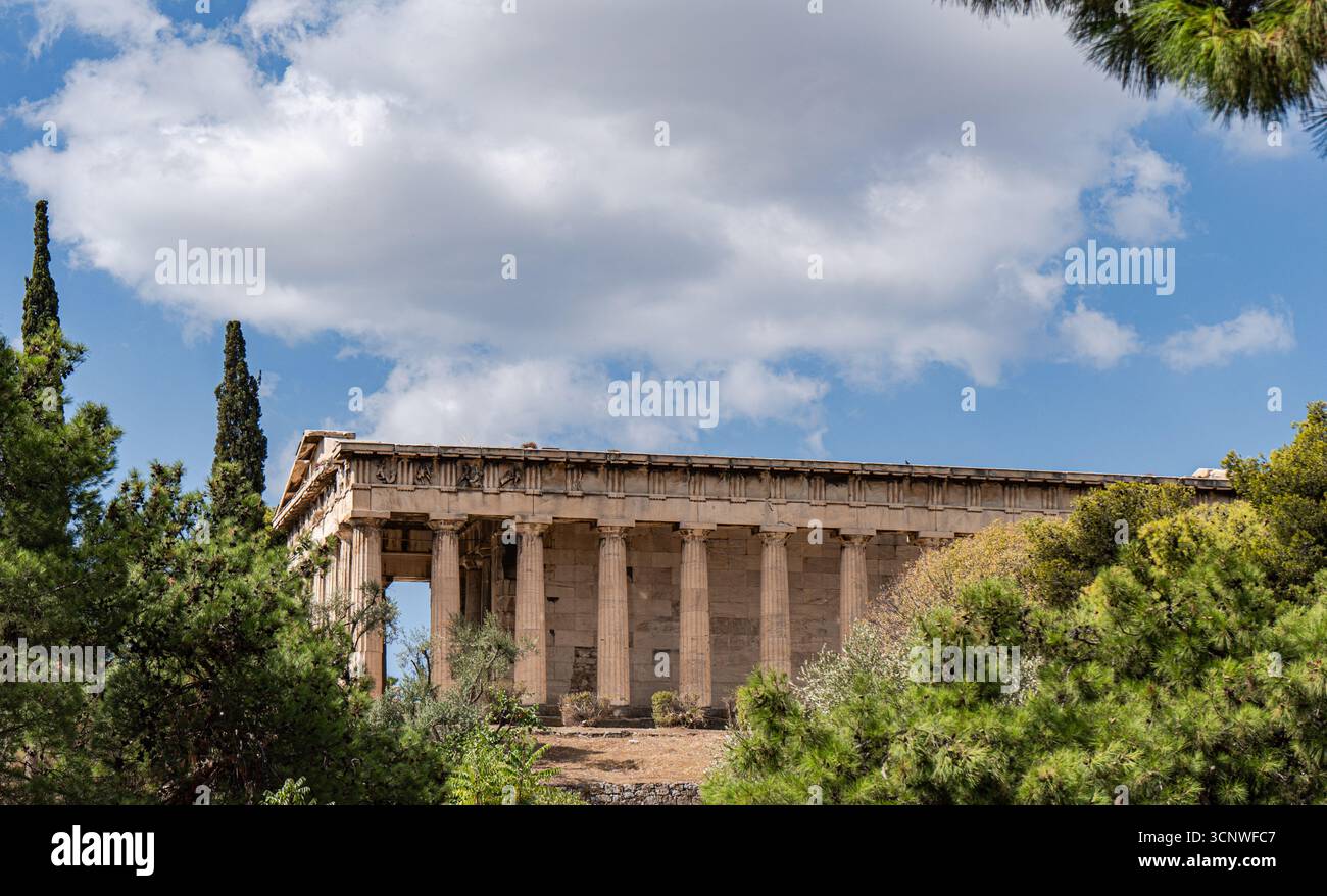 Vista di un antico tempio greco ad Atene, con le sue maestose colonne e l'architettura classica. La struttura e' circondata da lussureggiante vegetazione Foto Stock