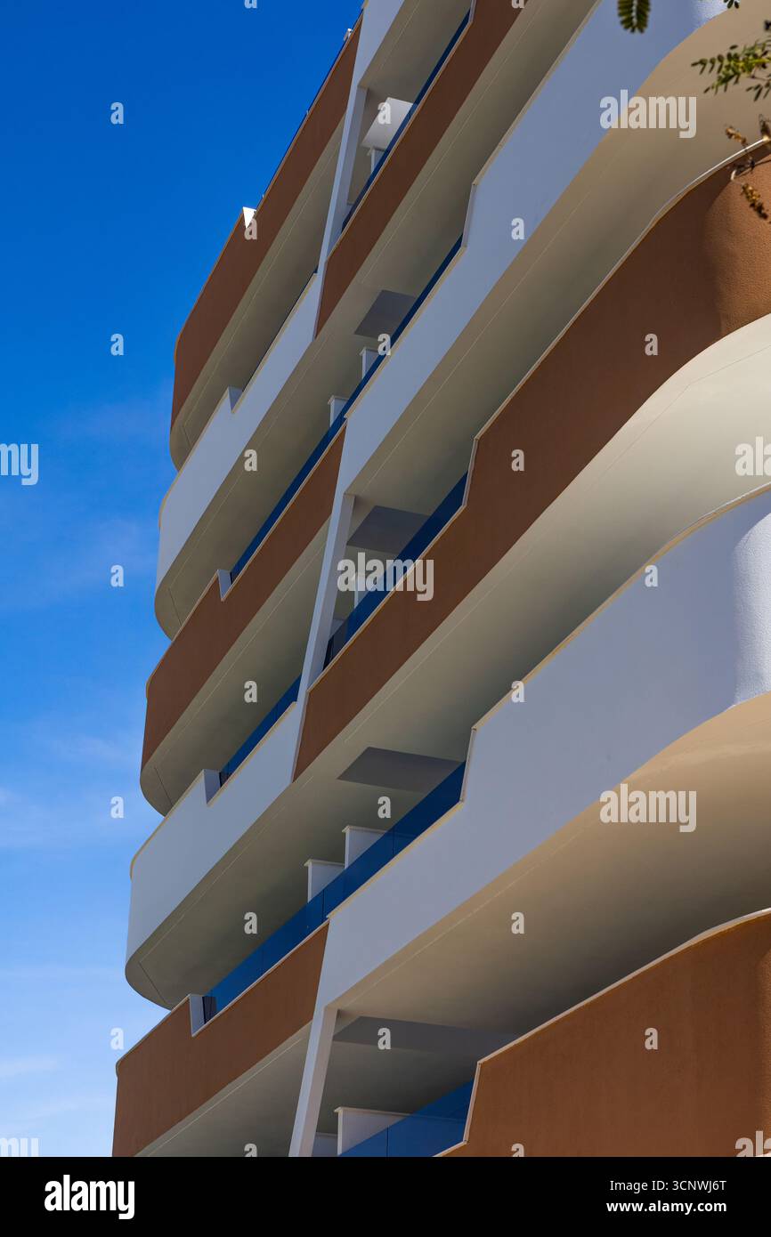 Moderno edificio di appartamenti a Los Arenales del Sol, Elche, con linee geometriche e design mediterraneo su un cielo azzurro limpido in una giornata di sole. Foto Stock