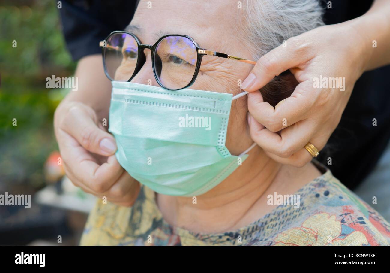 La nonna, di quasi 70 anni, si prendeva cura di sua nipote mentre si rilassava al parco. Persone che indossano una maschera protettiva. Foto Stock