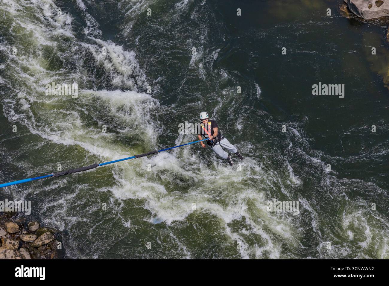 Melgaco, Portogallo - 06 giugno 2025: Saltatori bungee saltano da una scogliera rocciosa sul fiume Minho circondata da rocce nel nord del Portogallo. Foto Stock