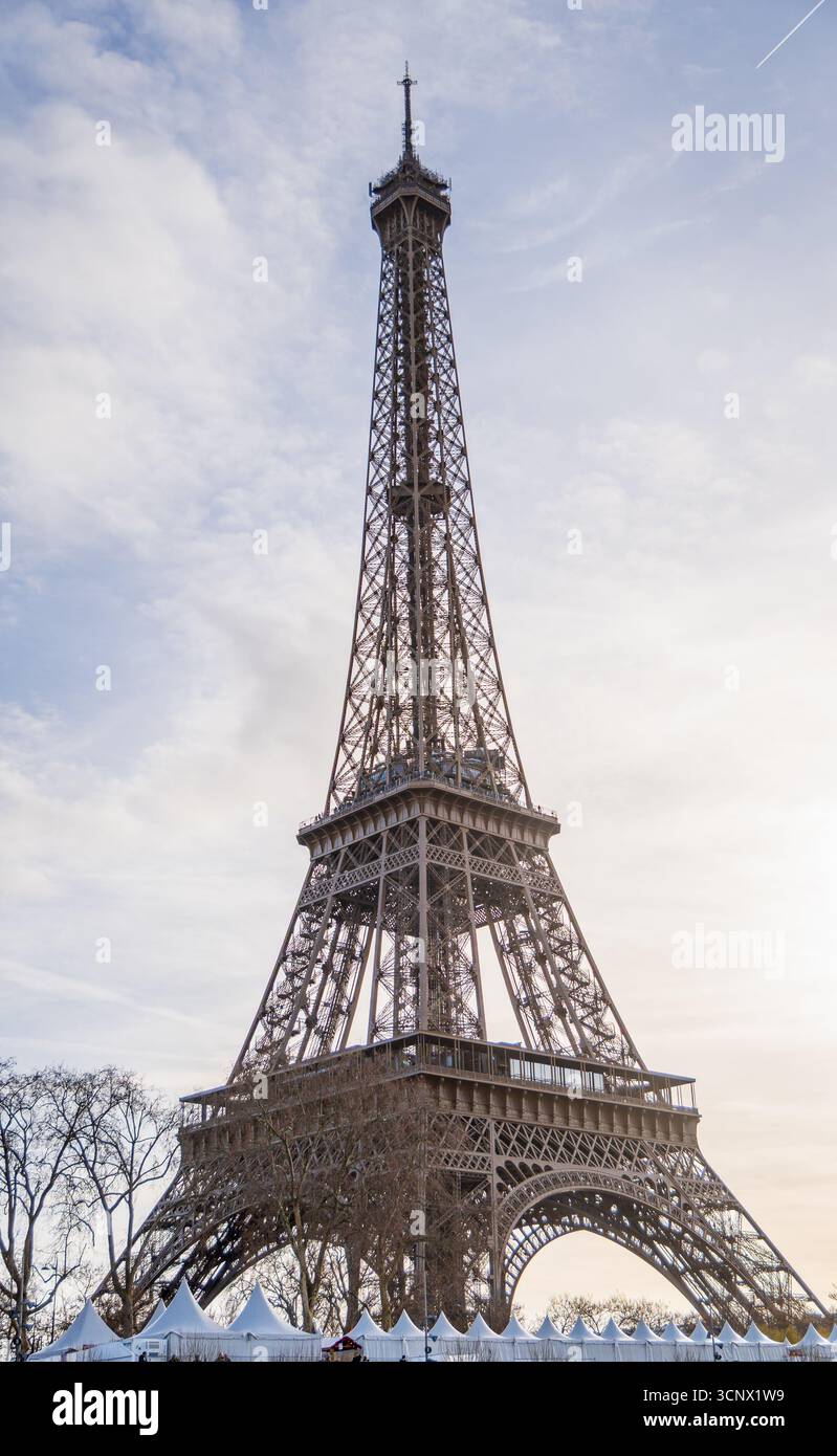La Torre Eiffel si erge maestosamente contro un cielo mattutino parzialmente nuvoloso, creando una vista pittoresca perfetta per i turisti che esplorano Parigi. Il sereno Foto Stock