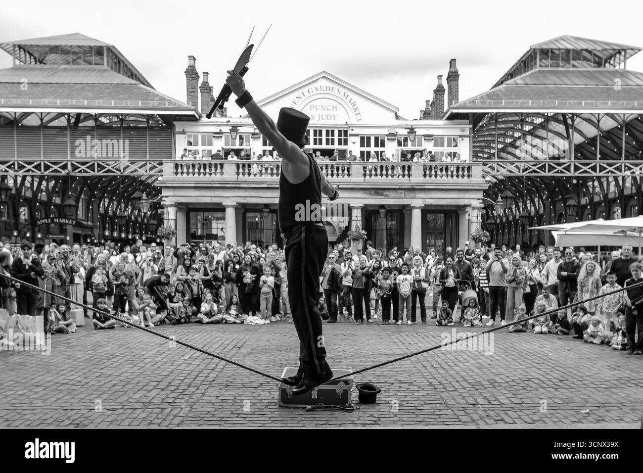 Londra, Regno Unito - 25 maggio 2025 : Vista di un artista di strada in equilibrio su una corda a Covent Garden Londra Regno Unito in bianco e nero Foto Stock