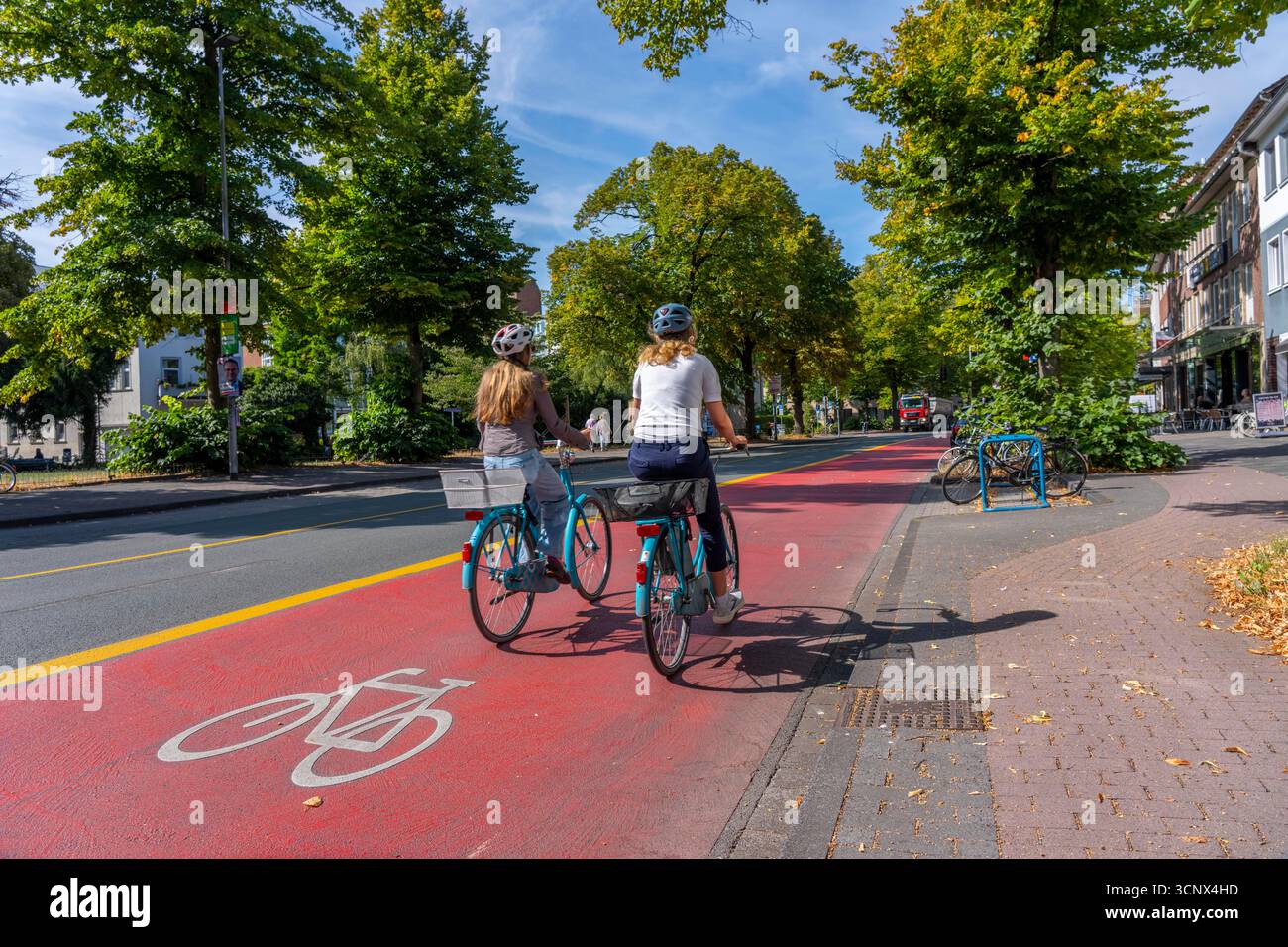 Pedalando a Münster, via Warendorf, ampio asfalto rosso contrassegnato come pista ciclabile, pista ciclabile, codificato a colori per separarlo dalla corsia di circolazione delle automobili, Foto Stock