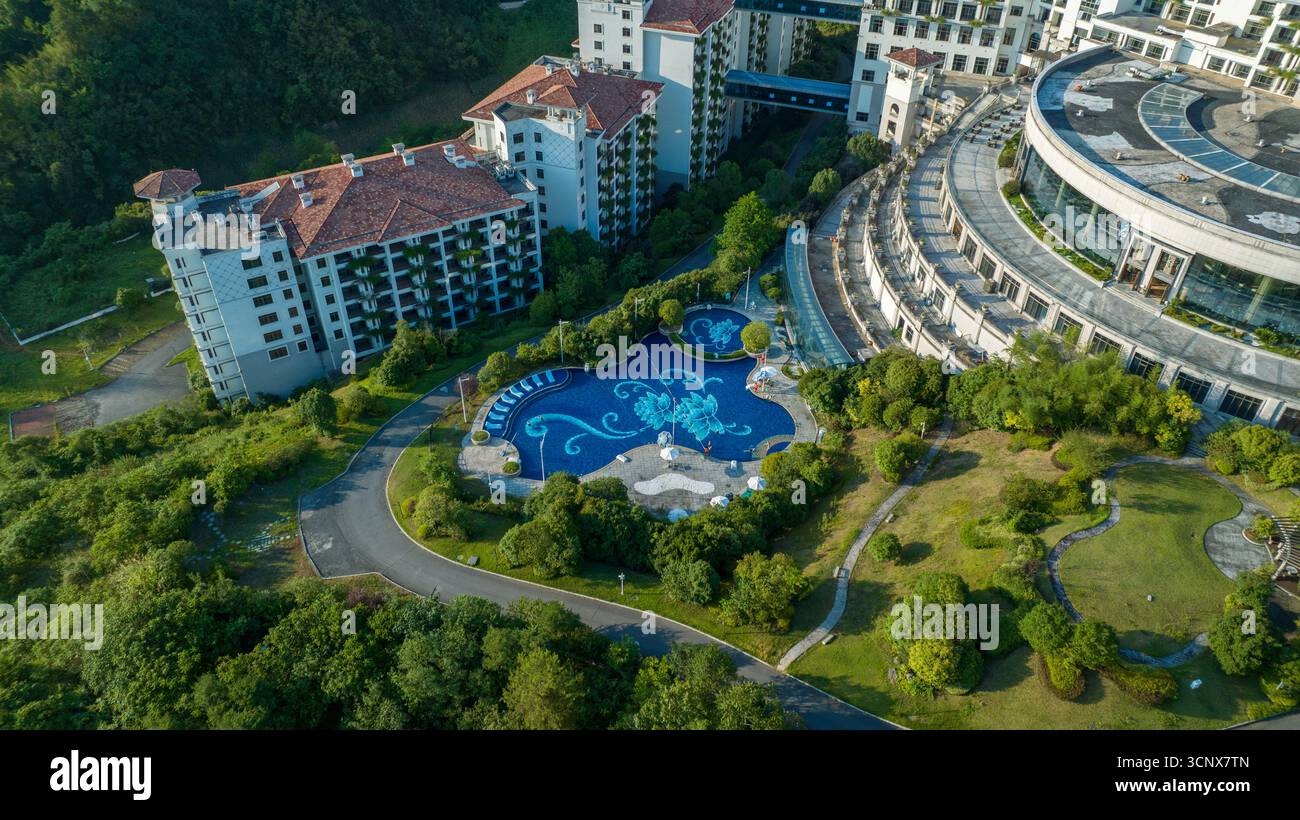 Vista aerea di un resort opulento con una piscina dal design serpeggiante e lussureggianti dintorni verdi, Zhangjiajie, Hunan, Cina. Foto Stock