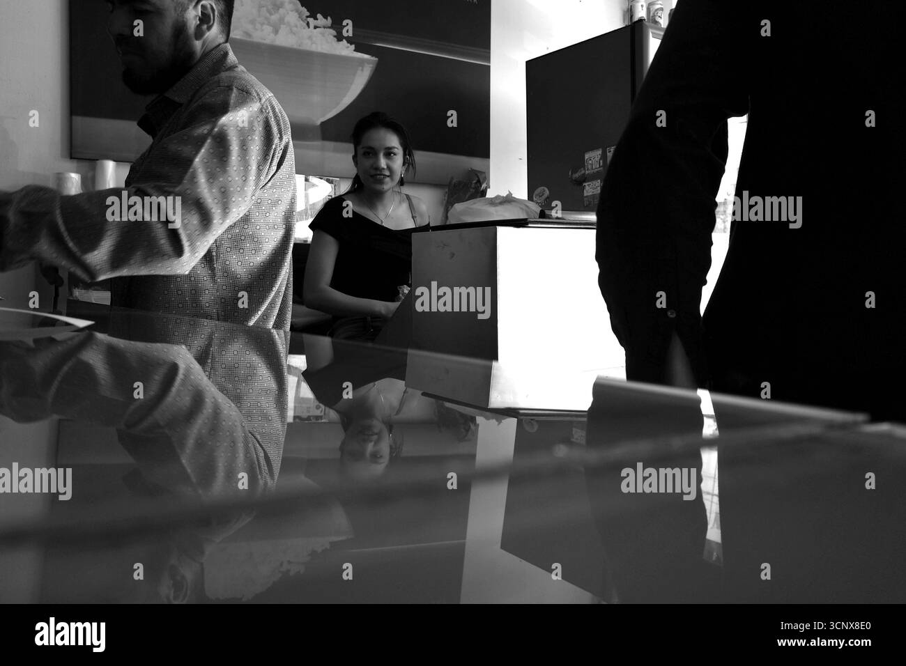 Il personale del ristorante e i clienti interagiscono presso un bancone informale di cibo messicano-giapponese Foto Stock