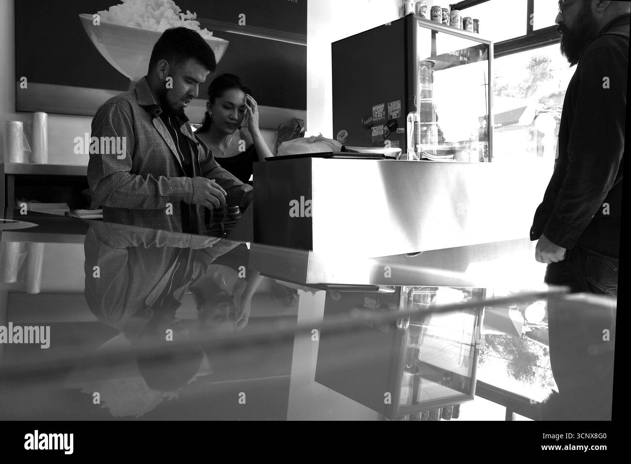 Il personale del ristorante e i clienti interagiscono presso un bancone informale di cibo messicano-giapponese Foto Stock