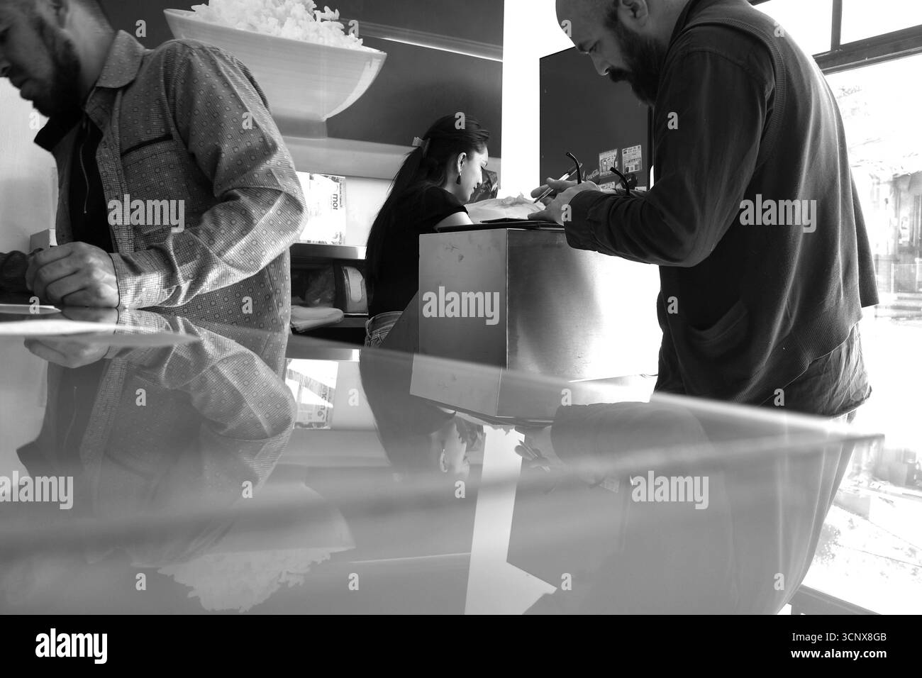 Il personale del ristorante e i clienti interagiscono presso un bancone informale di cibo messicano-giapponese Foto Stock