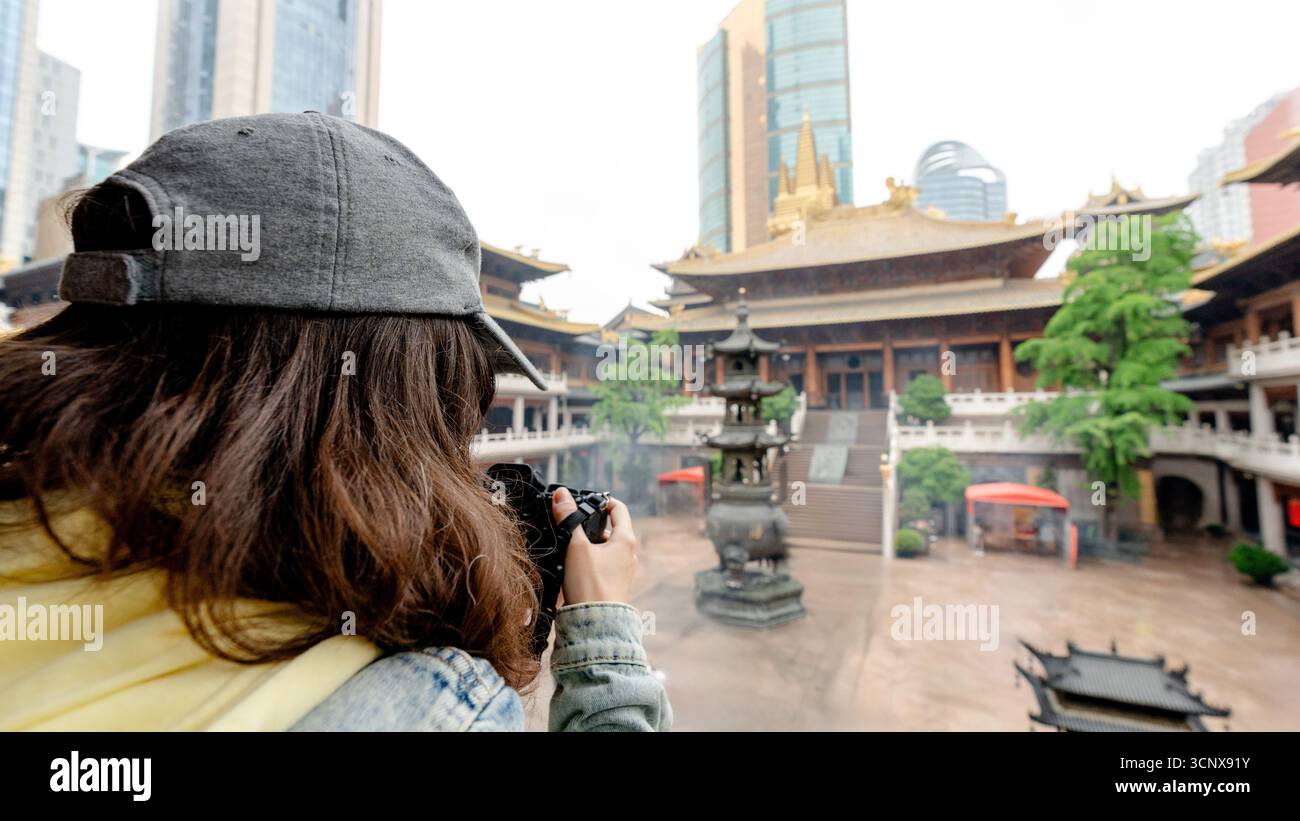 Un visitatore cattura l'antica architettura del Tempio di Jing'an, un importante tempio buddista a Shanghai, in Cina, che contrasta splendidamente con il moderno Foto Stock