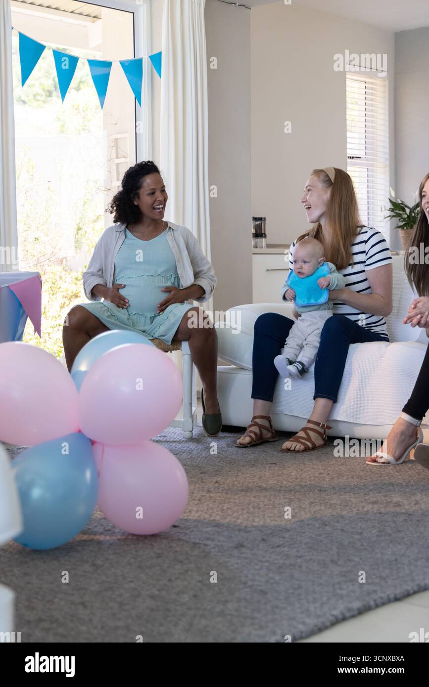 Amici diversi che si riuniscono a casa con palloncini, amici incinta con pancia, spazio copia Foto Stock