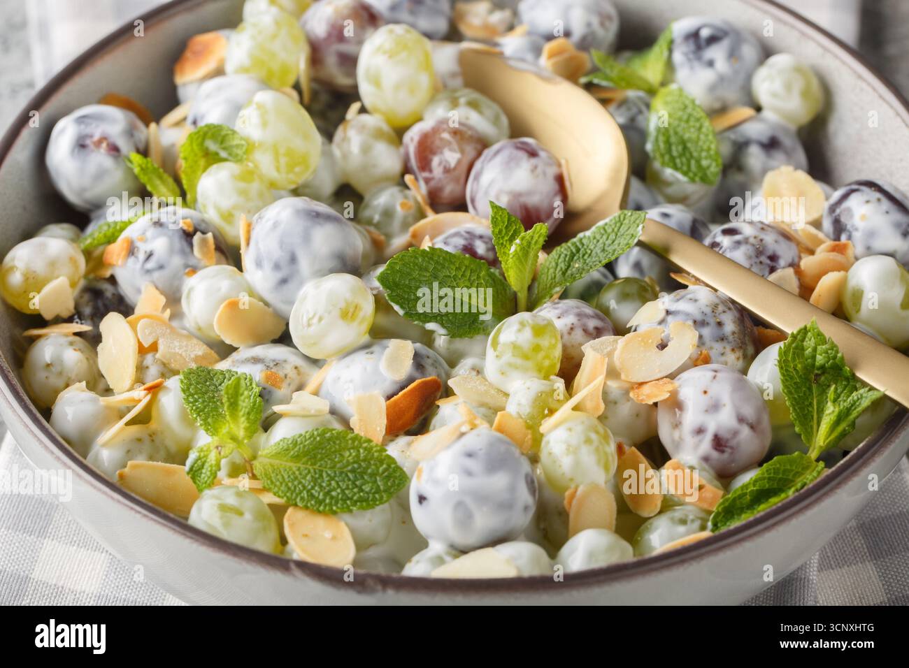 Insalata di uva dolce con mandorle e menta con condimento di yogurt da vicino in un piatto sul tavolo. Orizzontale Foto Stock