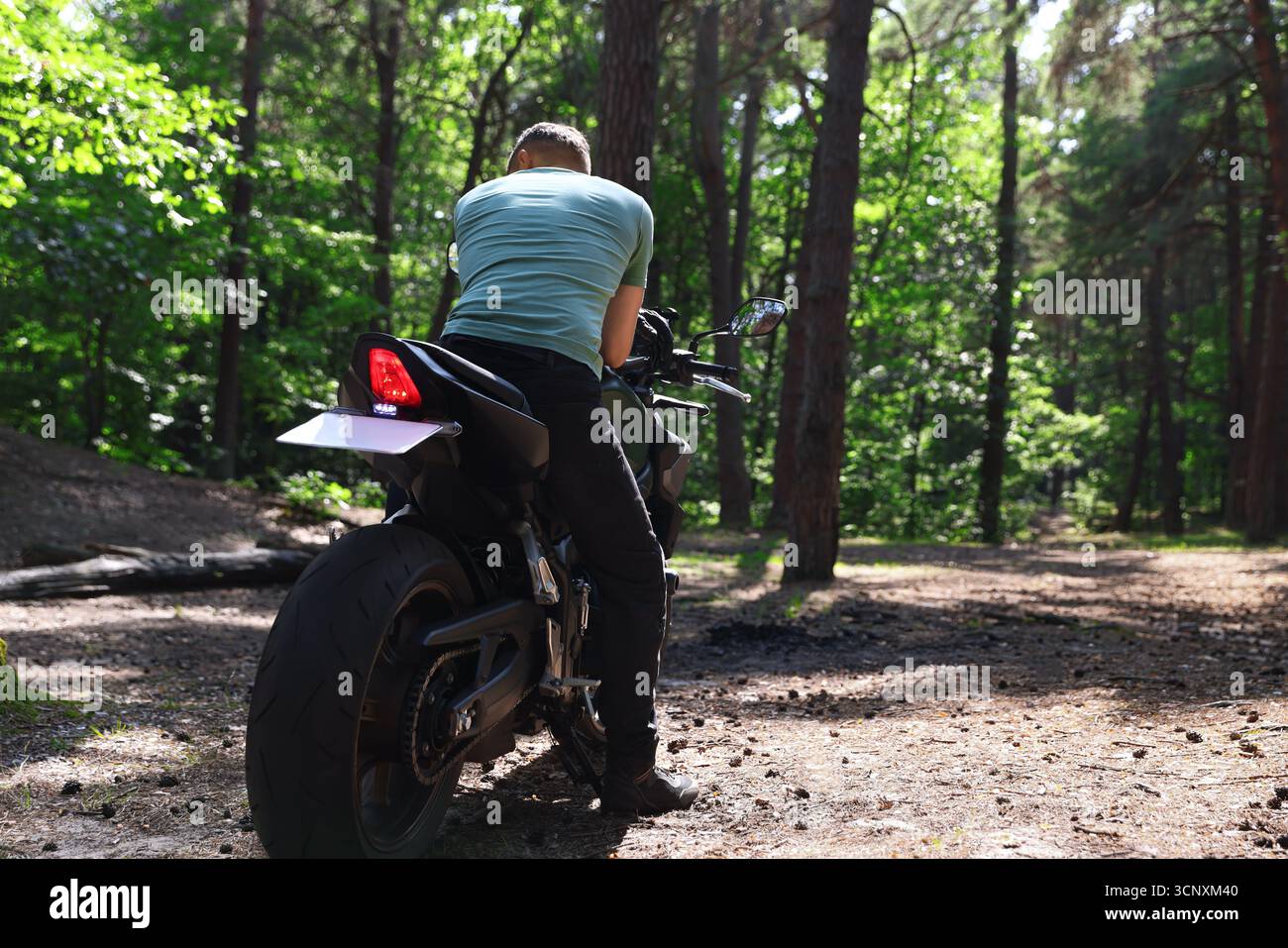 Giovane uomo con motocicletta moderna all'aperto, vista posteriore. Spazio per il testo Foto Stock