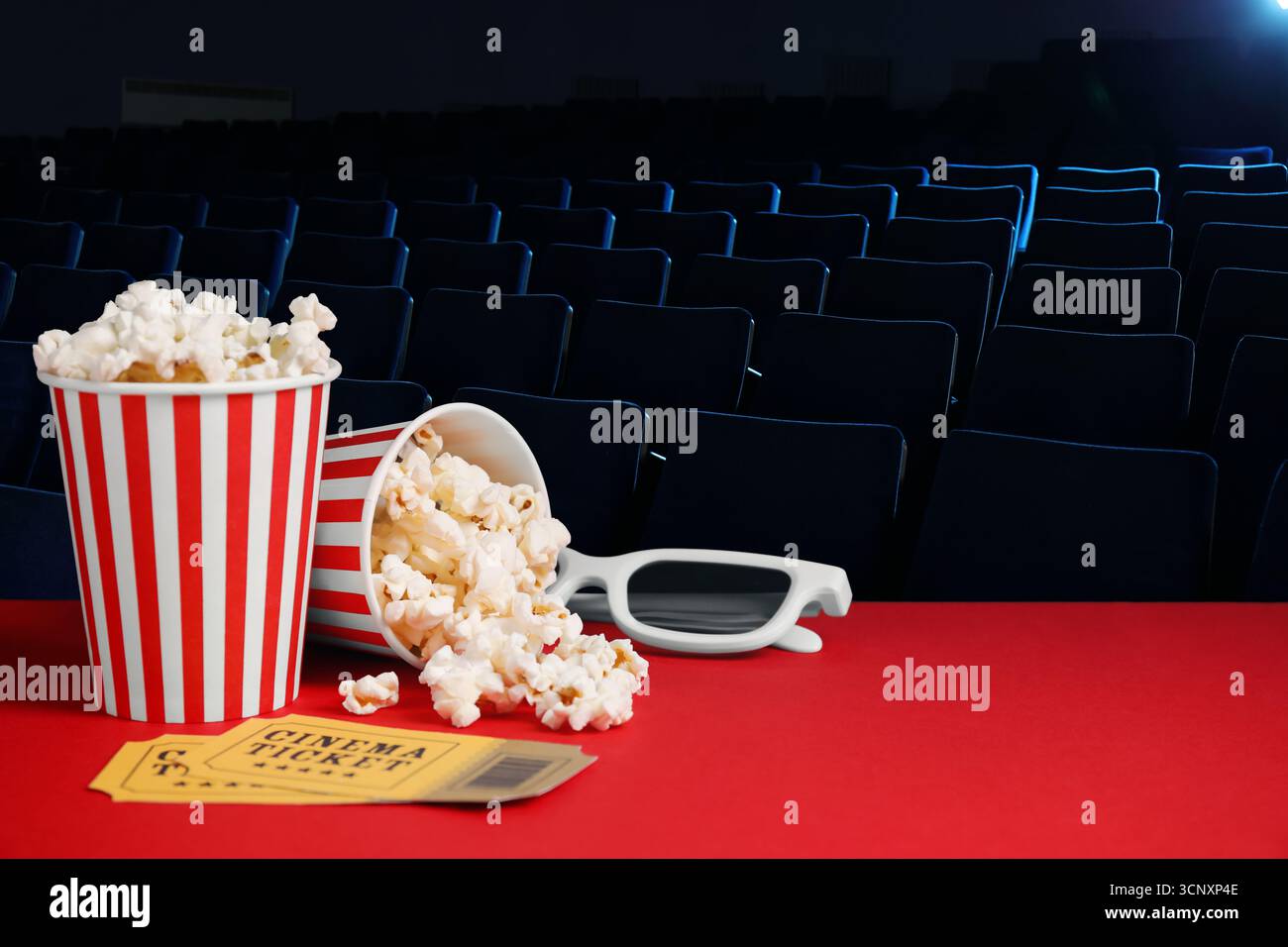 Secchielli di popcorn fresco, bicchieri 3D e biglietti per il cinema sul tavolo rosso nel cinema Dark Foto Stock
