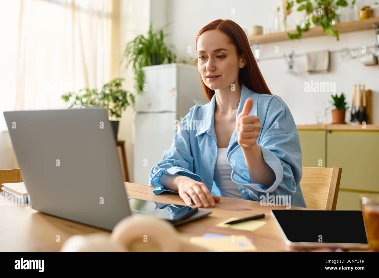 Un'insegnante di lingue dai capelli rossi si impegna online dalla sua accogliente casa. Foto Stock