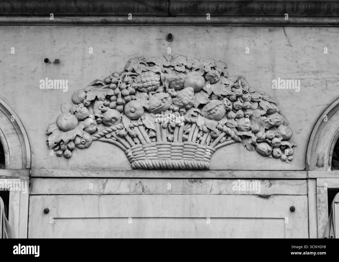 B&W Bassorilievo in marmo raffigurante un cesto traboccante pieno di frutta e fiori, che forma un festone decorativo, Genova, Italia Foto Stock