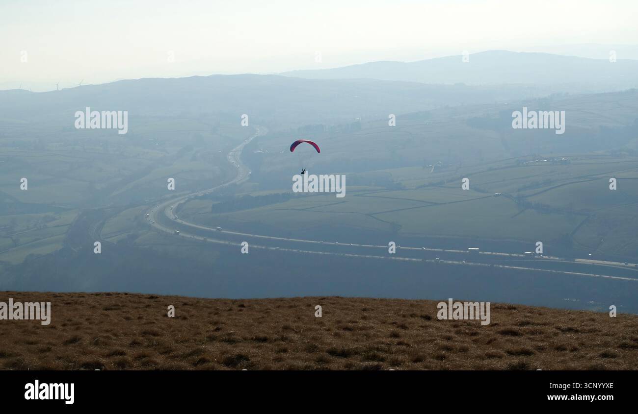 Volo in parapendio solitario contro Blue Sky dalla collina "Linghaw" sulla catena montuosa Howgills nel Lake District National Park, Cumbria, Inghilterra, Regno Unito. Foto Stock